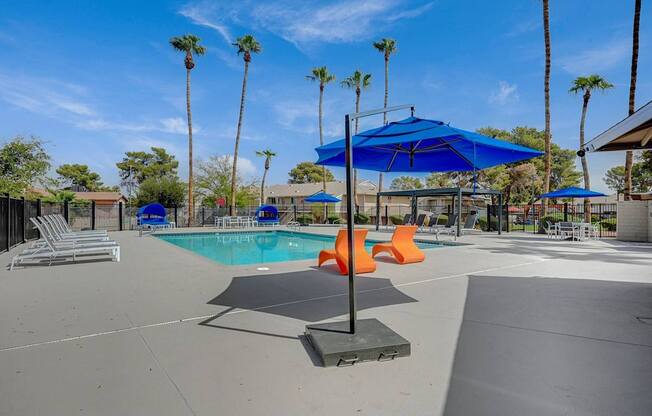 A pool area with a blue umbrella and orange chairs.