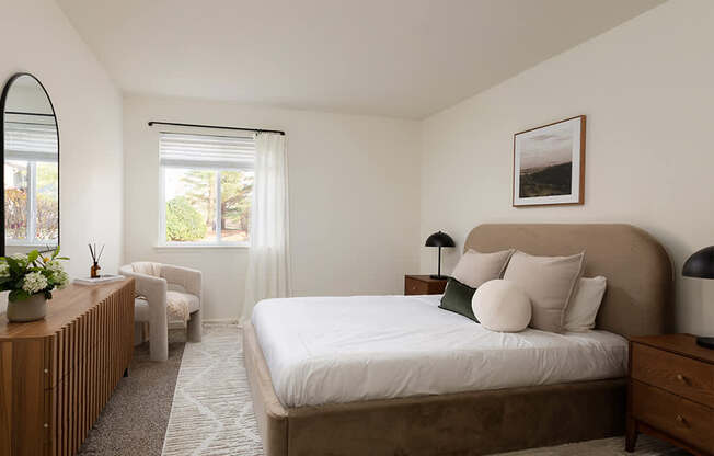 A bedroom with a large bed and a window with blinds.