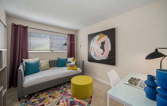 a living room with a couch and a desk in front of a window