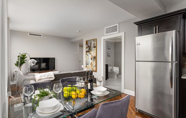 a kitchen and living room with a glass table and a refrigerator