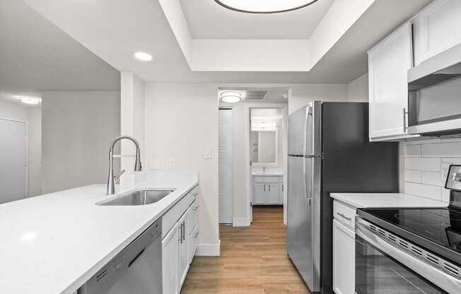 A modern kitchen with white cabinets and stainless steel appliances.