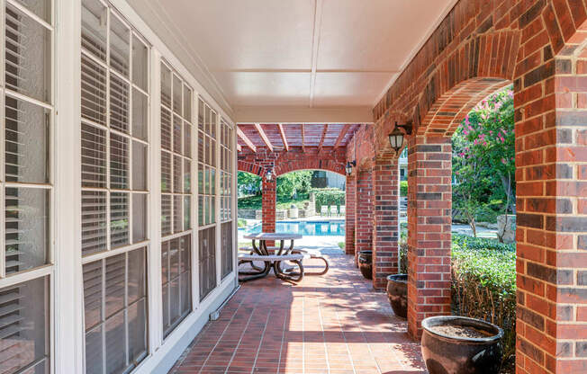 a covered porch with a table and a pool