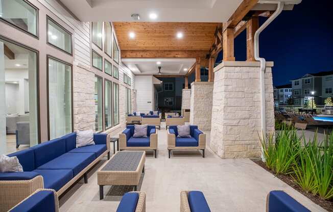 a patio with blue couches and chairs and a pool in the background at 55 Fifty at Northwest Crossing, Houston, 77092
