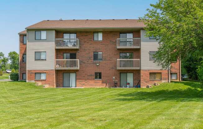 a brick apartment building with balconies and a green lawn