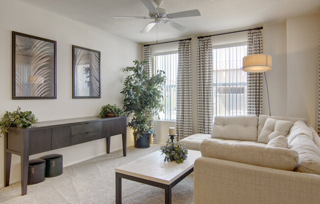 a living room with two windows and a ceiling fan