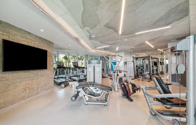 a gym with weights machines and a tv on the wall