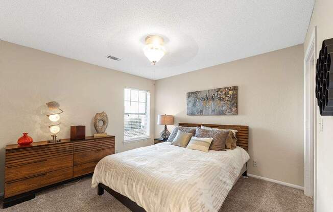 A bedroom with a bed, dresser, and window.