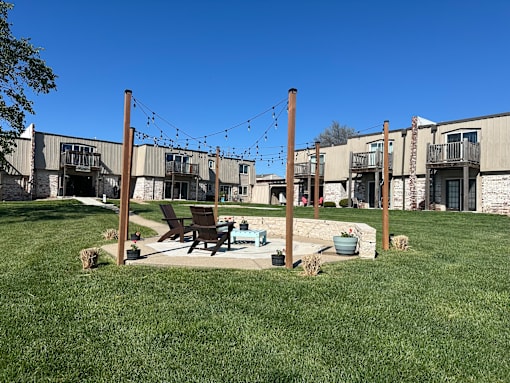 a patio with a fire pit in front of an apartment building