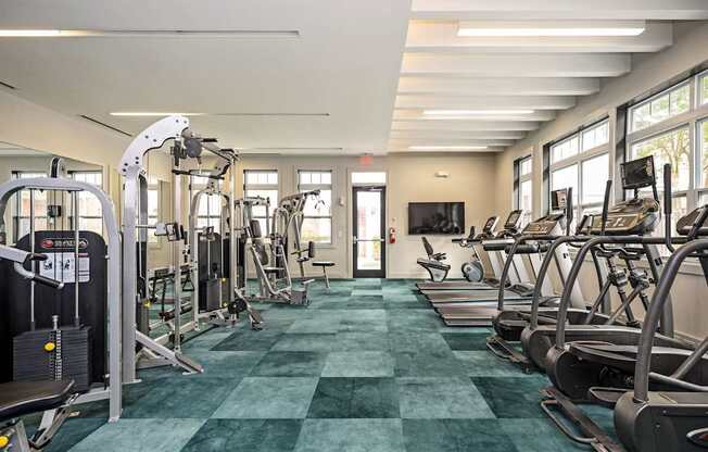 A gym with a variety of equipment including treadmills, weights, and exercise machines.