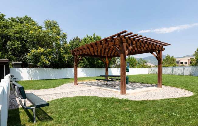 A wooden pergola is situated in a grassy area.