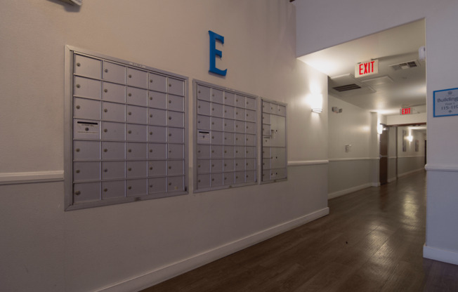 A hallway with a blue letter E on the wall and mailboxes on the wall.