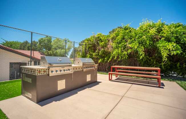 a picnic area with a barbecue grill and a bench at Acacia Gardens, Albuquerque, NM, 87111