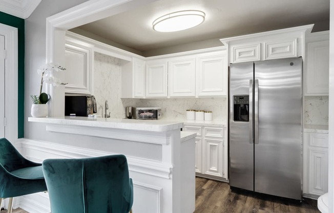 a kitchen with white cabinets and a silver refrigerator