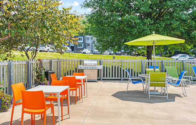 a patio with tables and chairs and a yellow umbrella