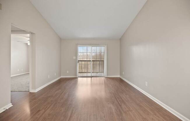 A room with wooden floors and a window with blinds.
