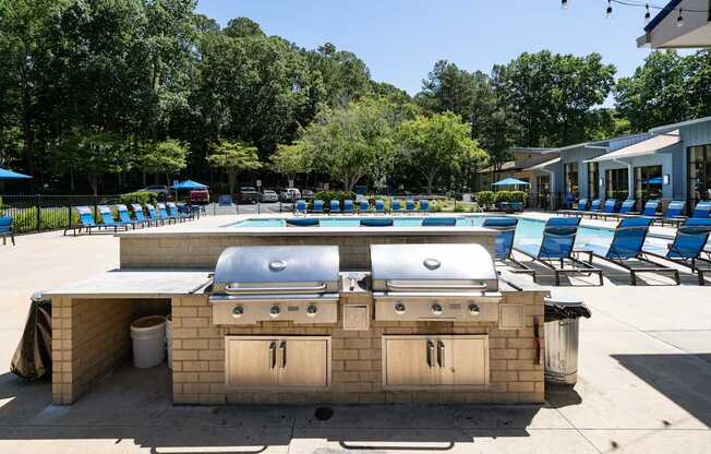 A barbecue grill is in the middle of a pool area.