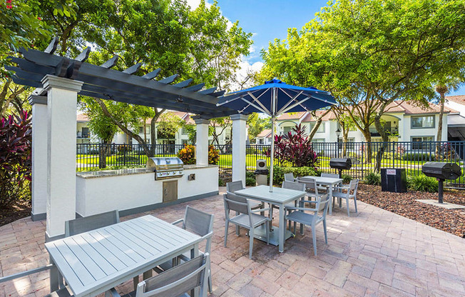 A patio with a table and chairs under a blue umbrella.