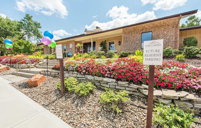 a building with a sign in front of a flower garden at Lodge of Overland Park Apartments, Overland Park , KS 66212