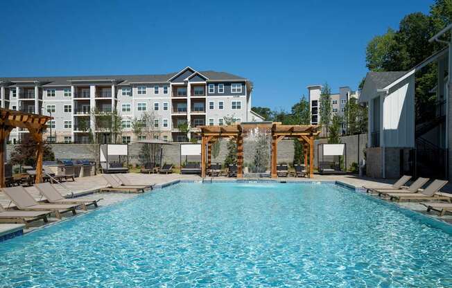 A large swimming pool with lounge chairs and a wooden pergola at The Ashton at East Park Apartments, Kennesaw, 30144