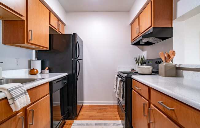 an empty kitchen with black appliances and wooden cabinets