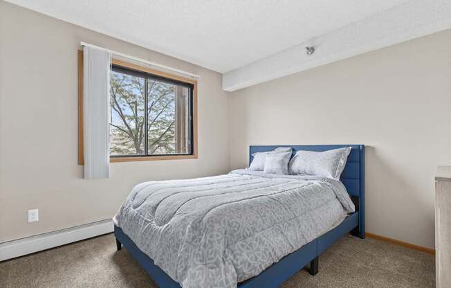 A bedroom with a bed, pillows, and a window.