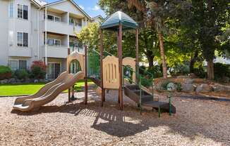 a playground with a slide and a swing set in front of an apartment building