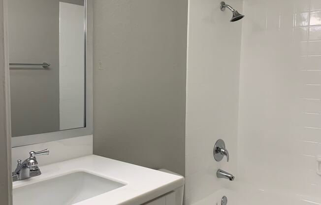 a white bathroom with a sink toilet and shower