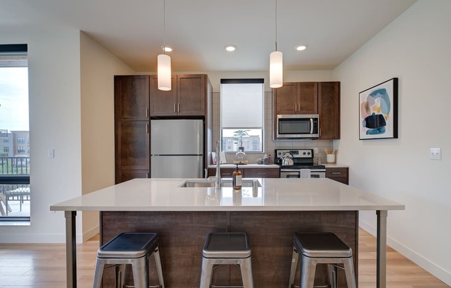an open kitchen with a large island with three stools at Statesman Apartments, Wisconsin 53132