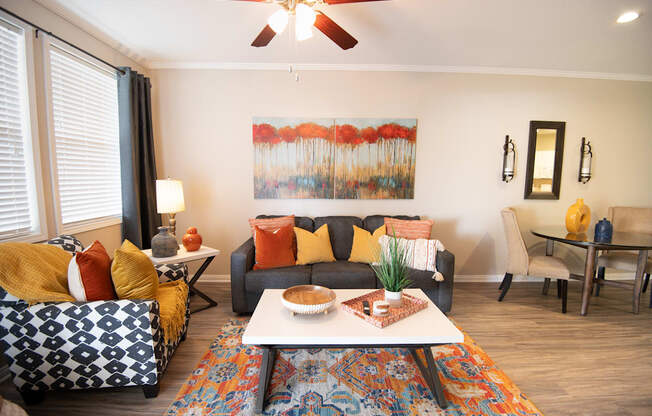 A living room with a couch, a chair, a coffee table, and a painting on the wall.
