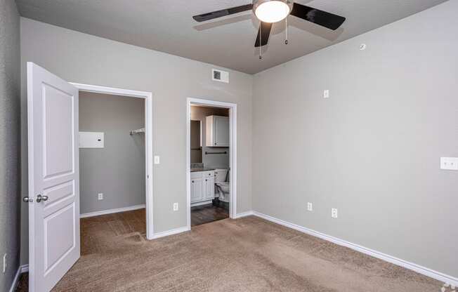 an empty room with a ceiling fan and a door to a bathroom