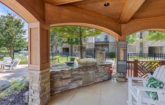 A patio with a stone wall and a grill.