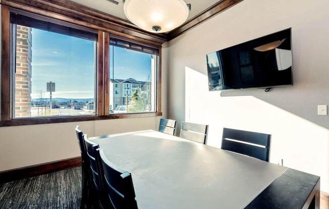 a conference room with a table and chairs and a tv on the wall