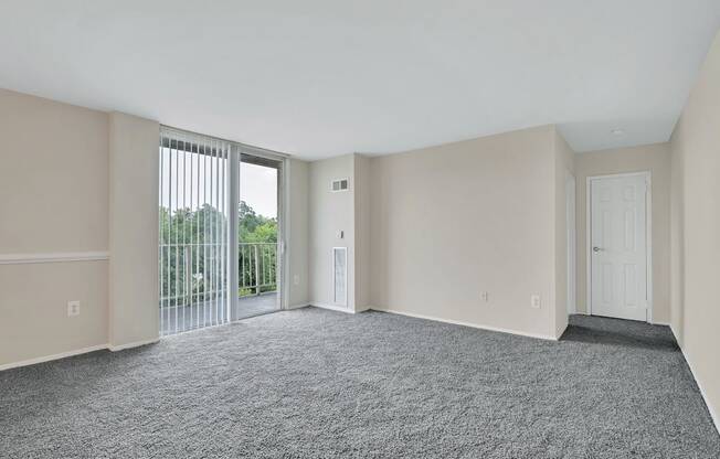 an empty living room with a sliding glass door to a balcony