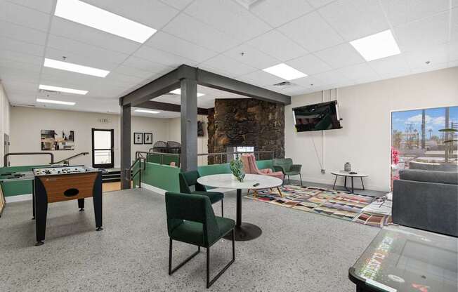 A room with a foosball table, chairs, and a television.