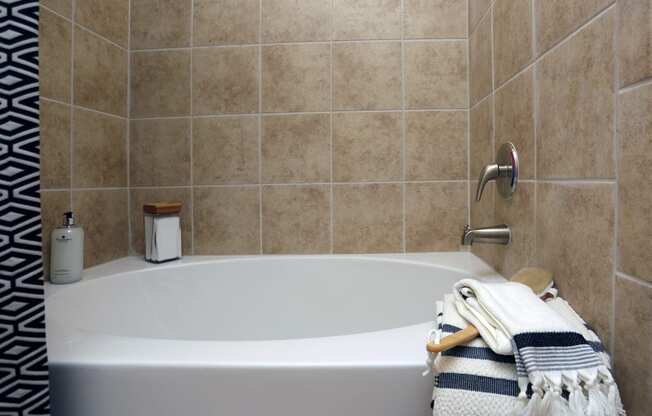 a white bath tub in a tiled bathroom