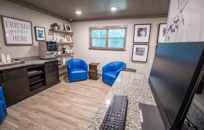 A room with a desk, chairs, and a computer.