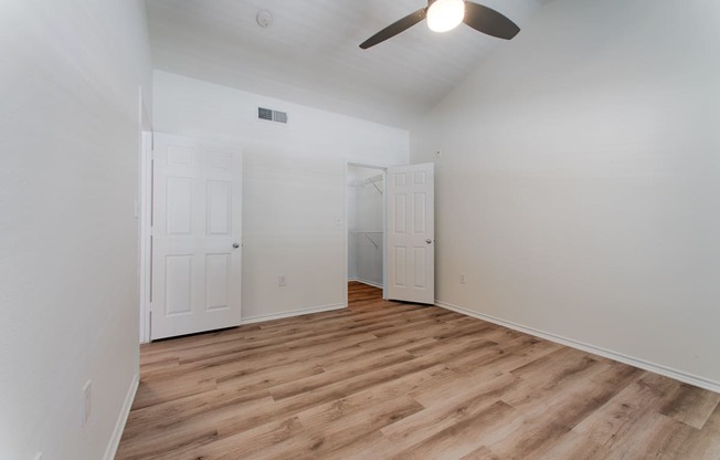 a bedroom with hardwood floors and white walls