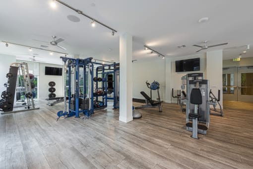 a gym with weights and cardio equipment and a tv