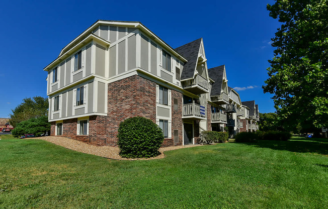 A large building with a brick base and white siding at Old Monterey Apartments, Springfield, MO