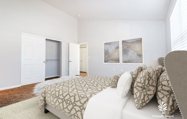 a bedroom with white walls and a large bed with grey and white bedding