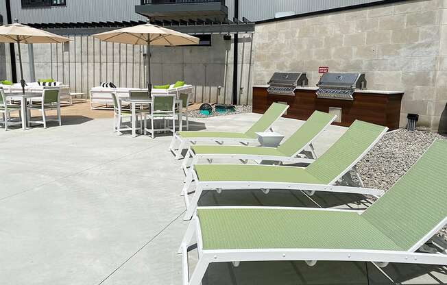 Row of light green lounge chairs and table with umbrellas near the pool at Haven at Uptown.