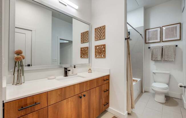 A bathroom with a white counter top and wooden cabinets.