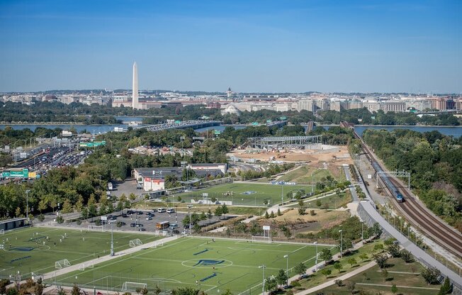 an aerial view of a football field in a city with a river in the background at The Acadia at Metropolitan Park, Arlington, Virginia