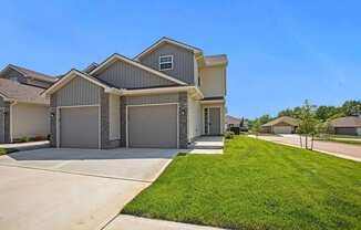 the front of a house with a driveway and a lawn