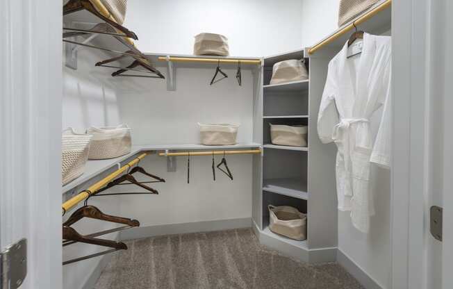 a walk in closet with a white wall and shelves filled with shoes and hangers