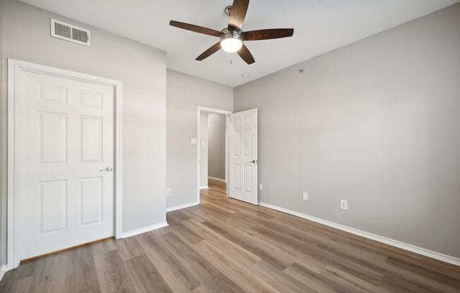 an empty living room with a ceiling fan and wood flooring