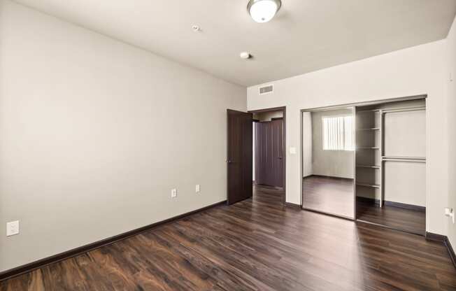 a living room with white walls and wooden floors and a closet