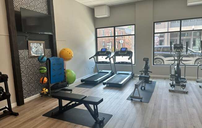 a gym with treadmills and weights on a wooden floor