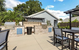 a patio with a table and chairs and a barbecue grill