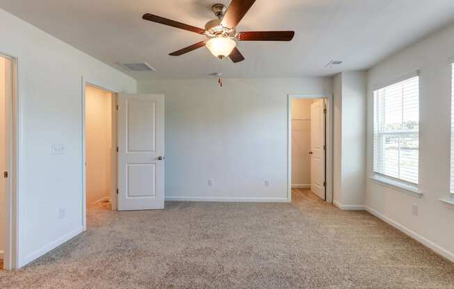 an empty living room with a ceiling fan and window